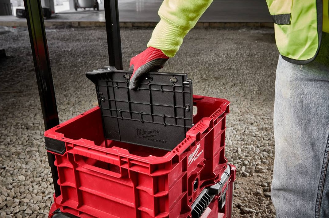 Red rugged storage crate with black impact-resistant divider panel for tool storage and workshop organization systems