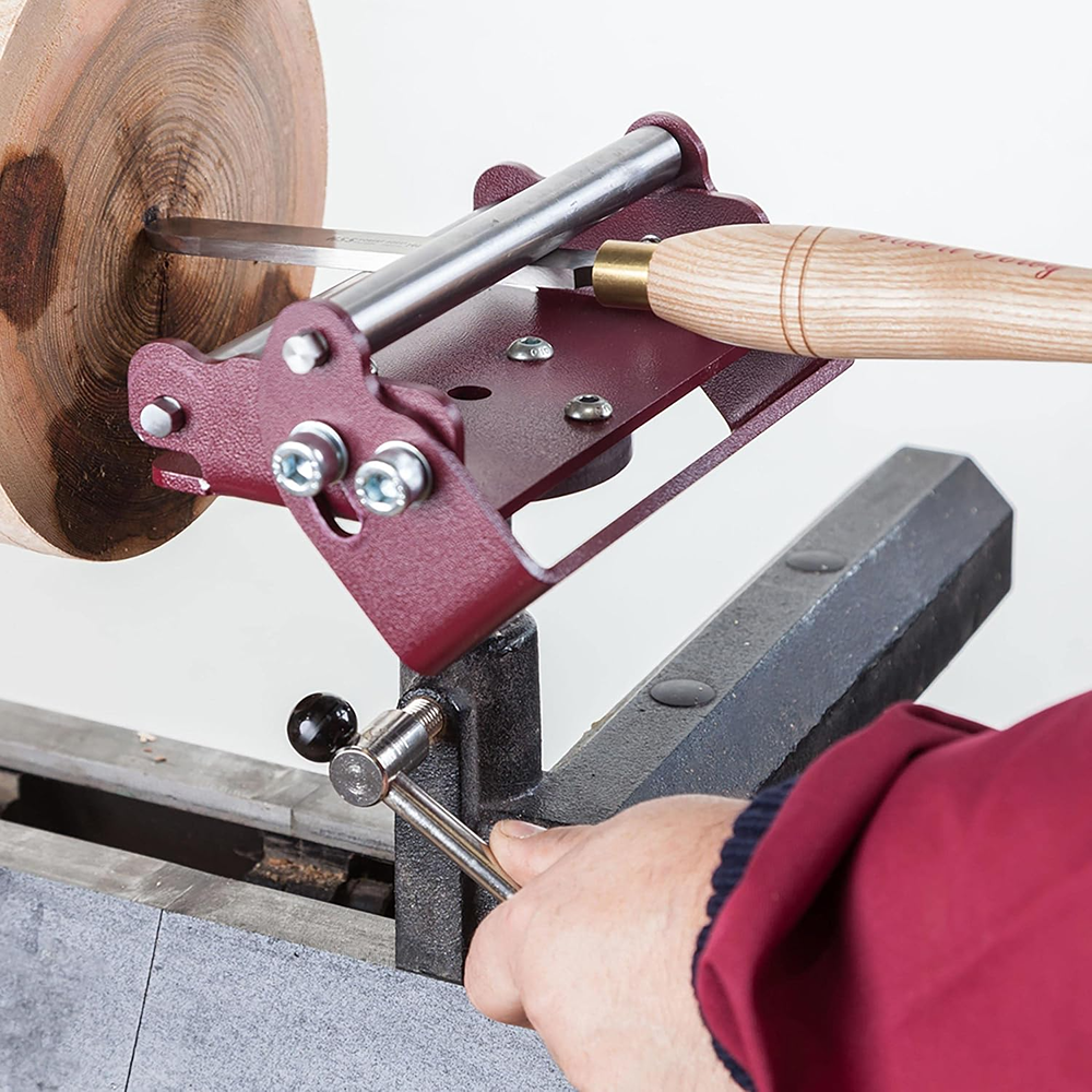 Red metal steady rest supporting a turning tool shaping a wooden bowl on a lathe for home improvement tasks