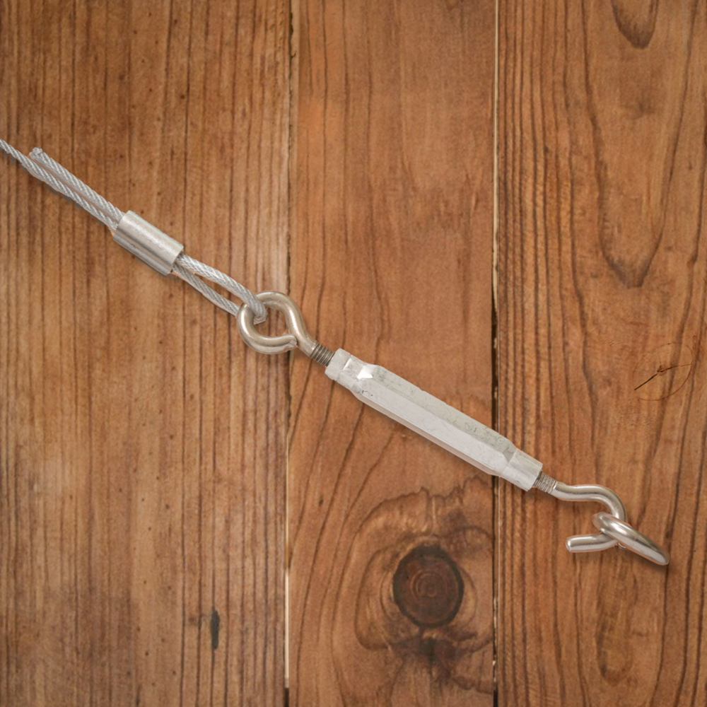 Stainless steel hook and eye turnbuckle connected to cable wire on wood surface for home improvement use