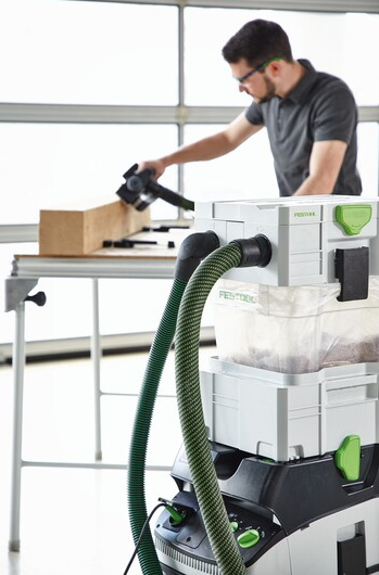 Woodworker using a Festool dust extractor with disposable liner for dust management in woodworking tools and home improvement