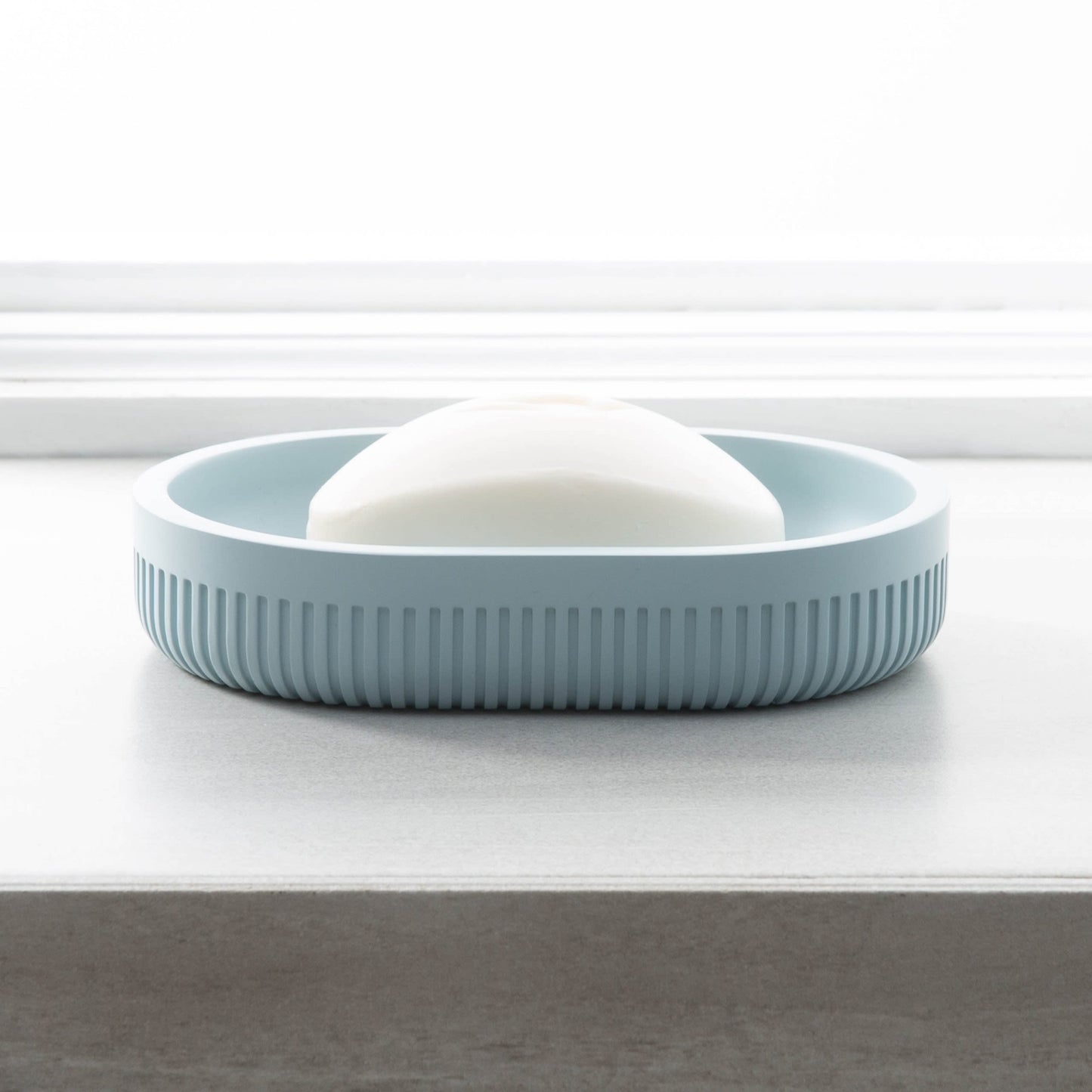 Blue resin soap dish with textured sides holding white soap, suitable for bathroom and bath accessory collections