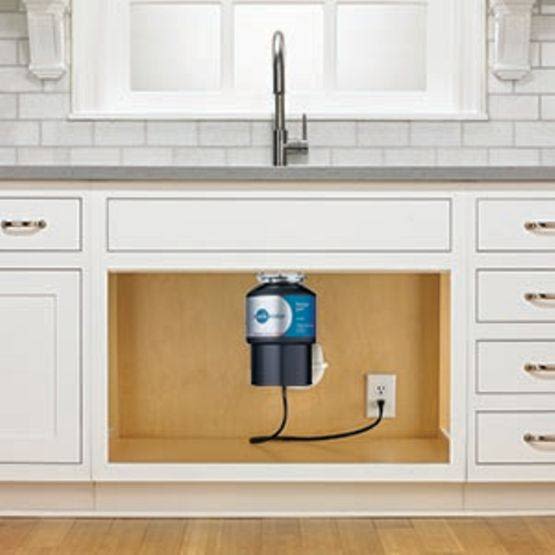 InSinkErator Badger® 1HP garbage disposal installed under kitchen sink with white cabinetry and tiled backsplash for home improvement.