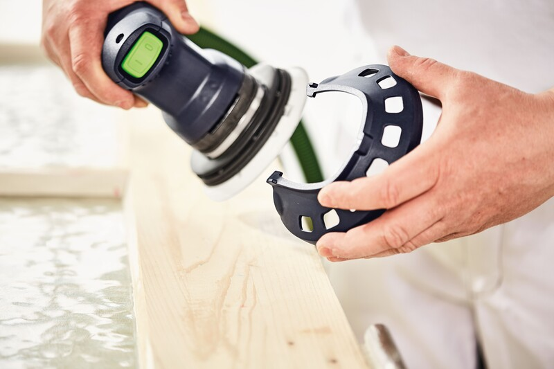 Hands fitting a black plastic edge protector onto a handheld power sander in woodworking tool accessories collection