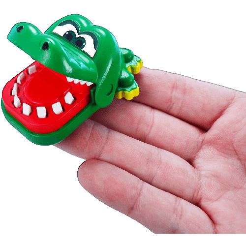 Small green plastic crocodile toy held on fingers with wide open jaw showing white teeth for playfun.