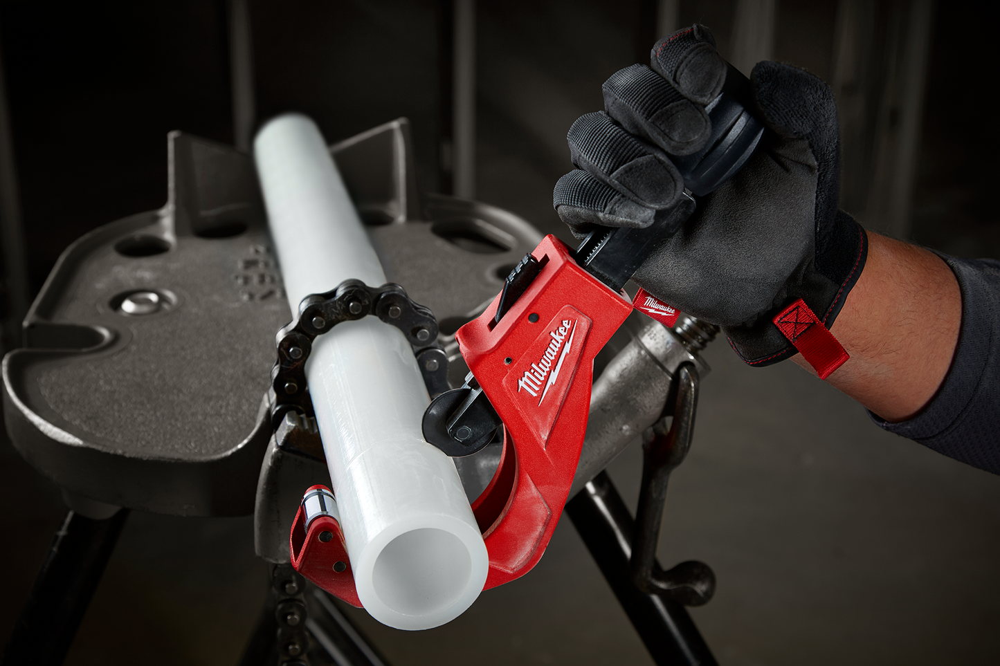 Red Milwaukee quick-adjust copper tubing cutter applied to white pipe, held by gloved hand for home improvement use