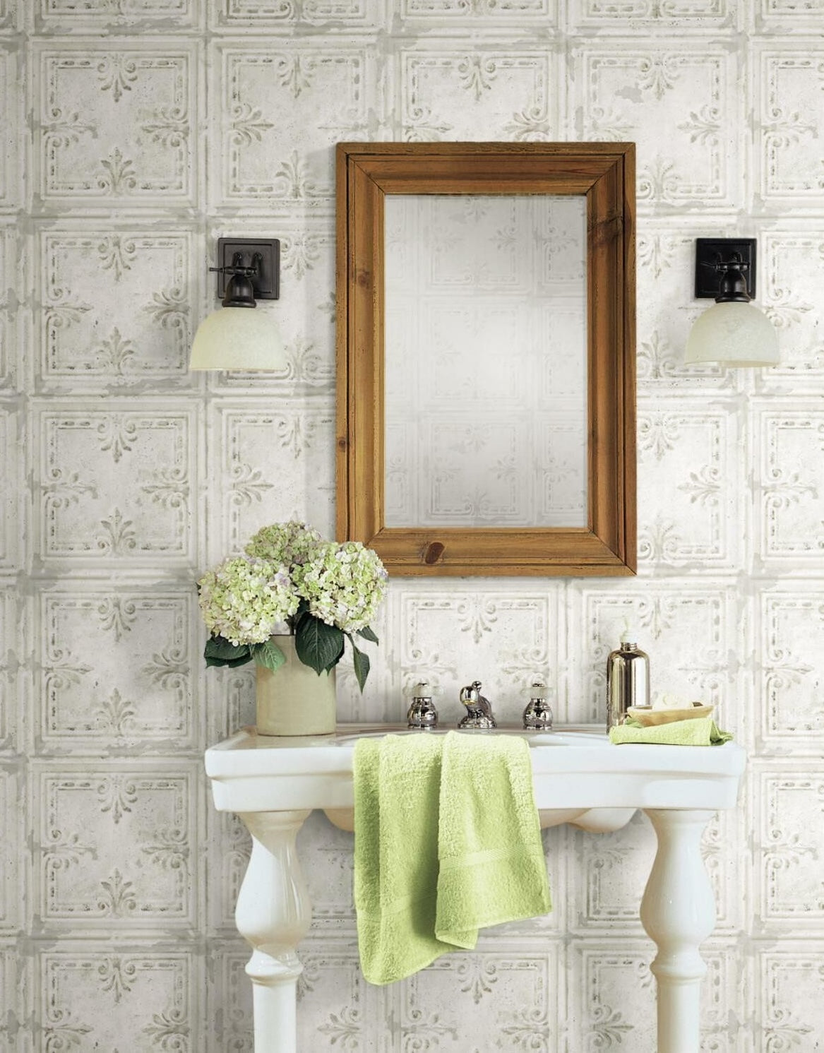 Bathroom sink area with framed mirror, floral arrangement, and embossed white tin tile peel-and-stick wallpaper