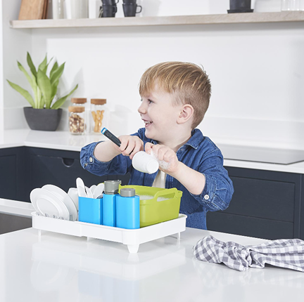 Child playing with Casdon Joseph Joseph Extend dish washing set featuring blue and green compartments on white base