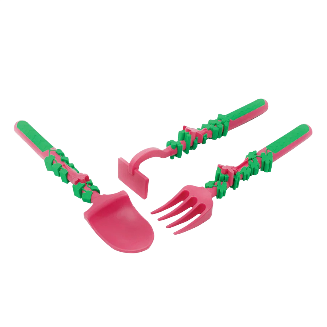 Small pink and green garden tools including a shovel, rake, and hoe designed for children’s outdoor play.