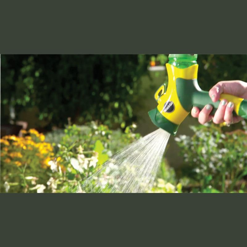 Handheld green and yellow garden sprayer watering blooming flowers in outdoor lawn and garden care setting
