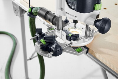 Close-up of a Festool router with dust extraction system mounted on light wood panel for precise woodworking tasks