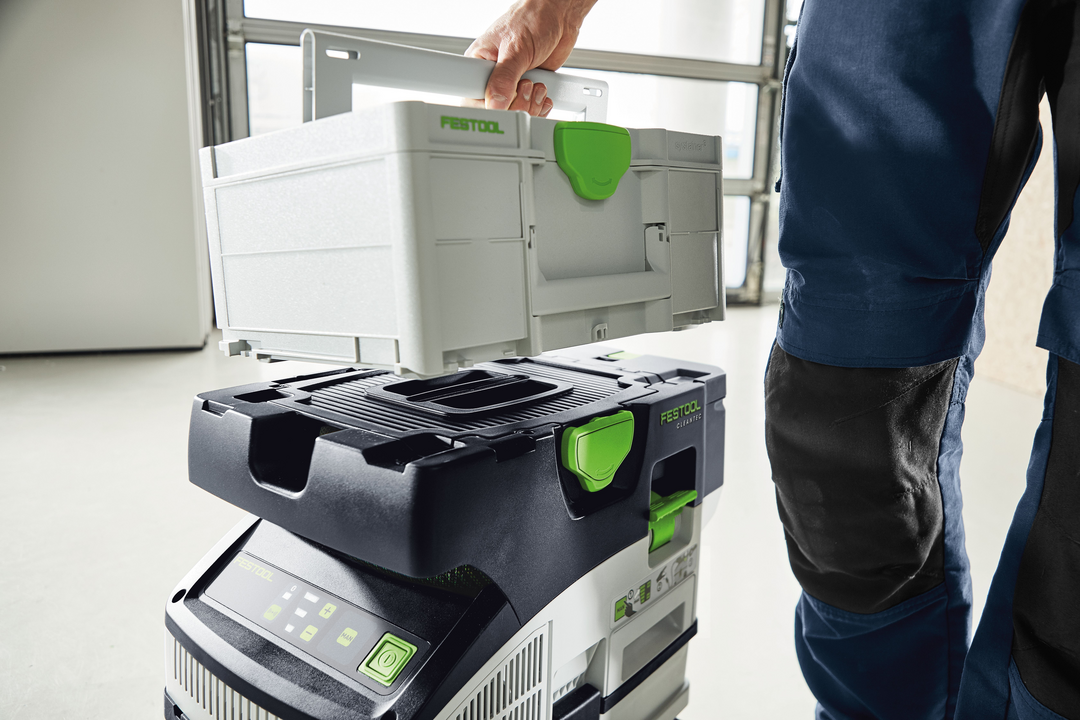 Person lifting modular storage box from cordless Festool dust extractor for tools and home improvement tasks