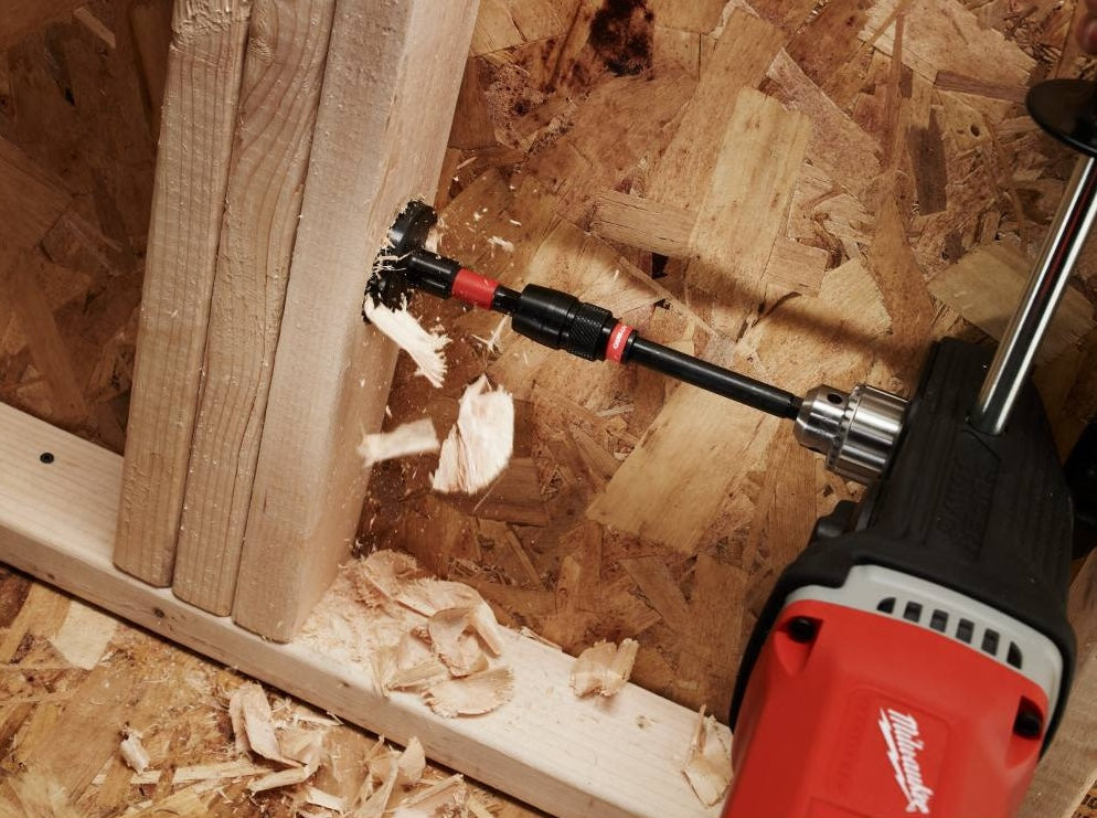 Power drill with selfeed bit cutting large hole in wood board for woodworking tools and home improvement use