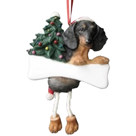 Black dachshund holiday ornament with dangling legs holding decorated Christmas tree and blank bone-shaped sign