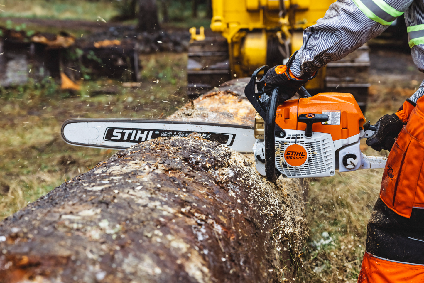 Orange and white STIHL chainsaw cutting large log outdoors with magnesium piston for tools and home improvement use