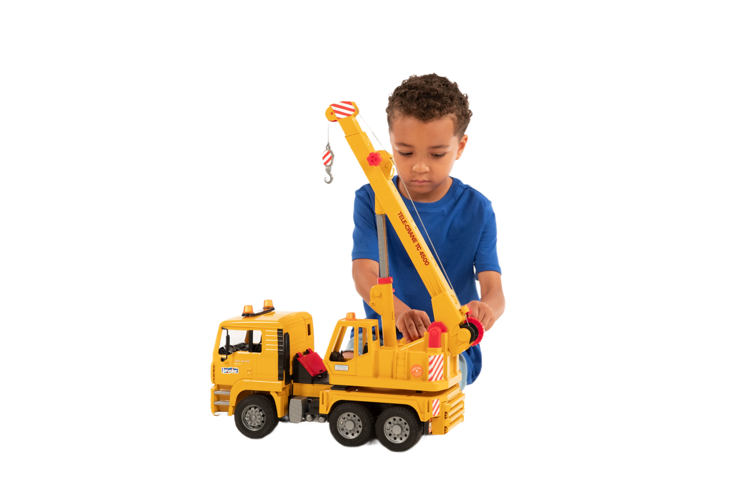 Child playing with yellow Bruder Toys MAN crane truck featuring movable boom and detailed cab design
