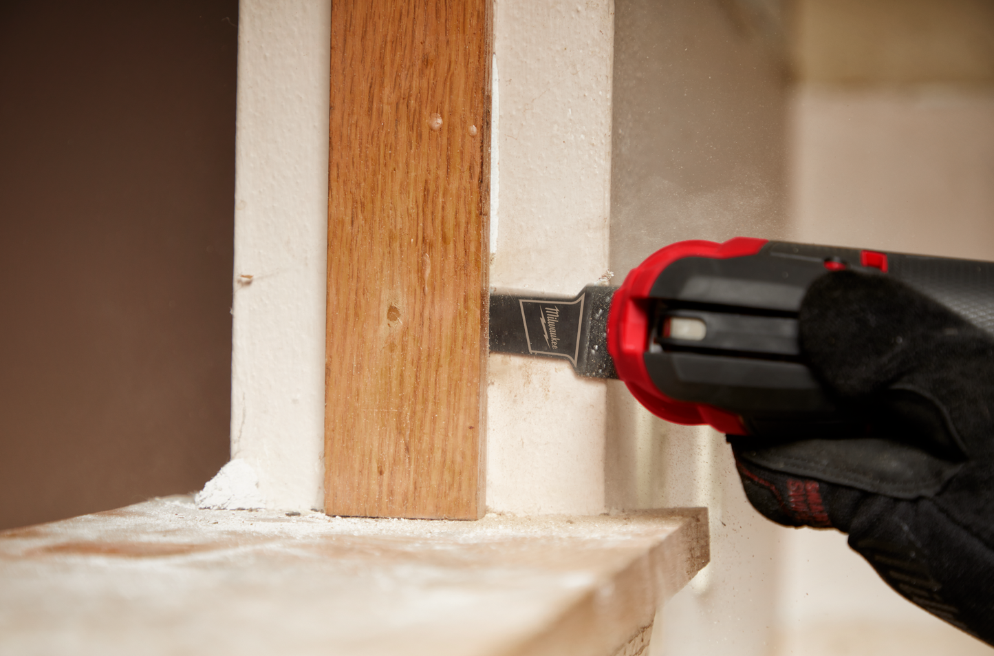 Power tool with Milwaukee titanium enhanced bi-metal blade cutting wood trim in a home improvement setting
