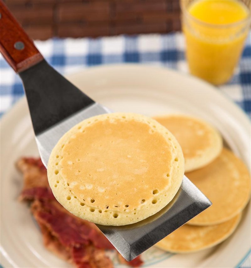 Restaurant-style stainless steel griddle spatula lifting a pancake with bacon and orange juice in background under $50 kitchenware