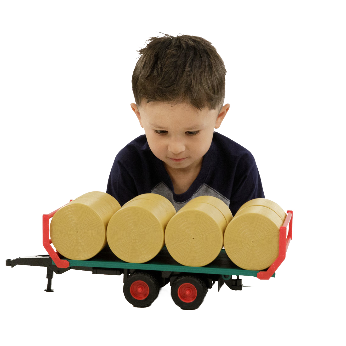 Young boy playing with green bale transport trailer toy carrying four round yellow bales from Bruder Toys collection