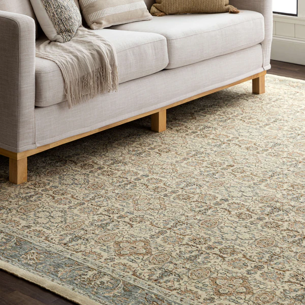 Soft grey area rug with detailed floral motifs under a modern beige sofa for elegant home improvement