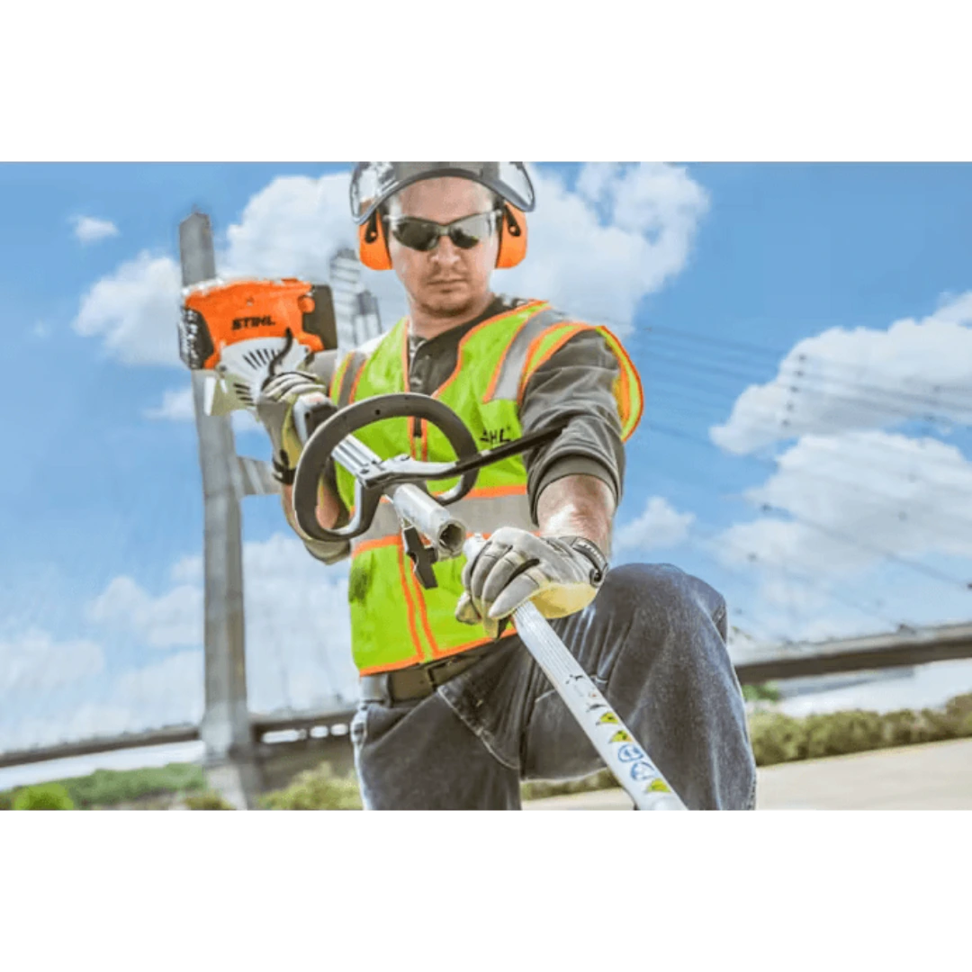 Worker in safety gear using orange STIHL KM 131 R KombiMotor outdoor power tool for home improvement tasks