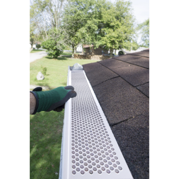 Brown vinyl snap-in gutter screen with perforated holes being installed on roof gutter for home improvement.