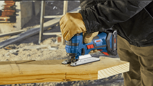 Worker using Bosch cordless jigsaw to cut wood plank in outdoor construction site tool accessories