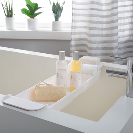 White expandable bathtub tray with non-slip grips, holding bath essentials for bathroom storage and home improvement under $50