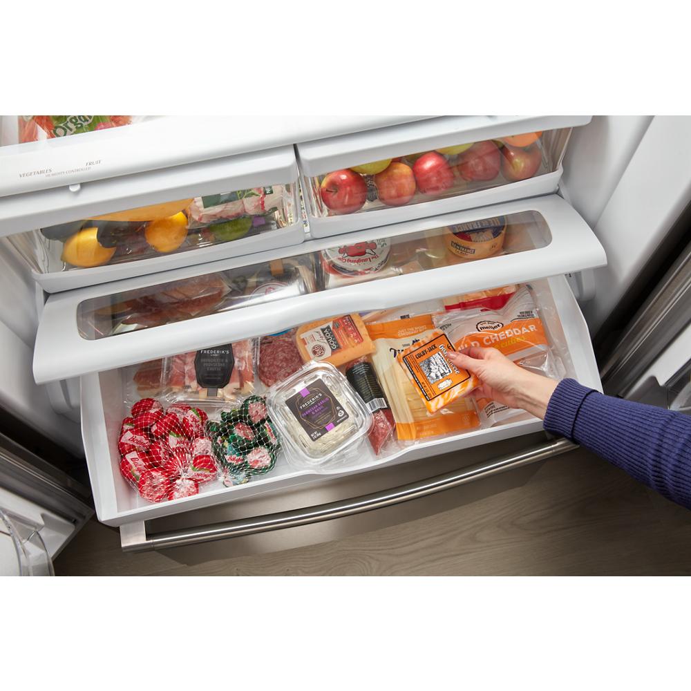 Open bottom freezer drawer of French door refrigerator stocked with groceries in modern kitchen appliances
