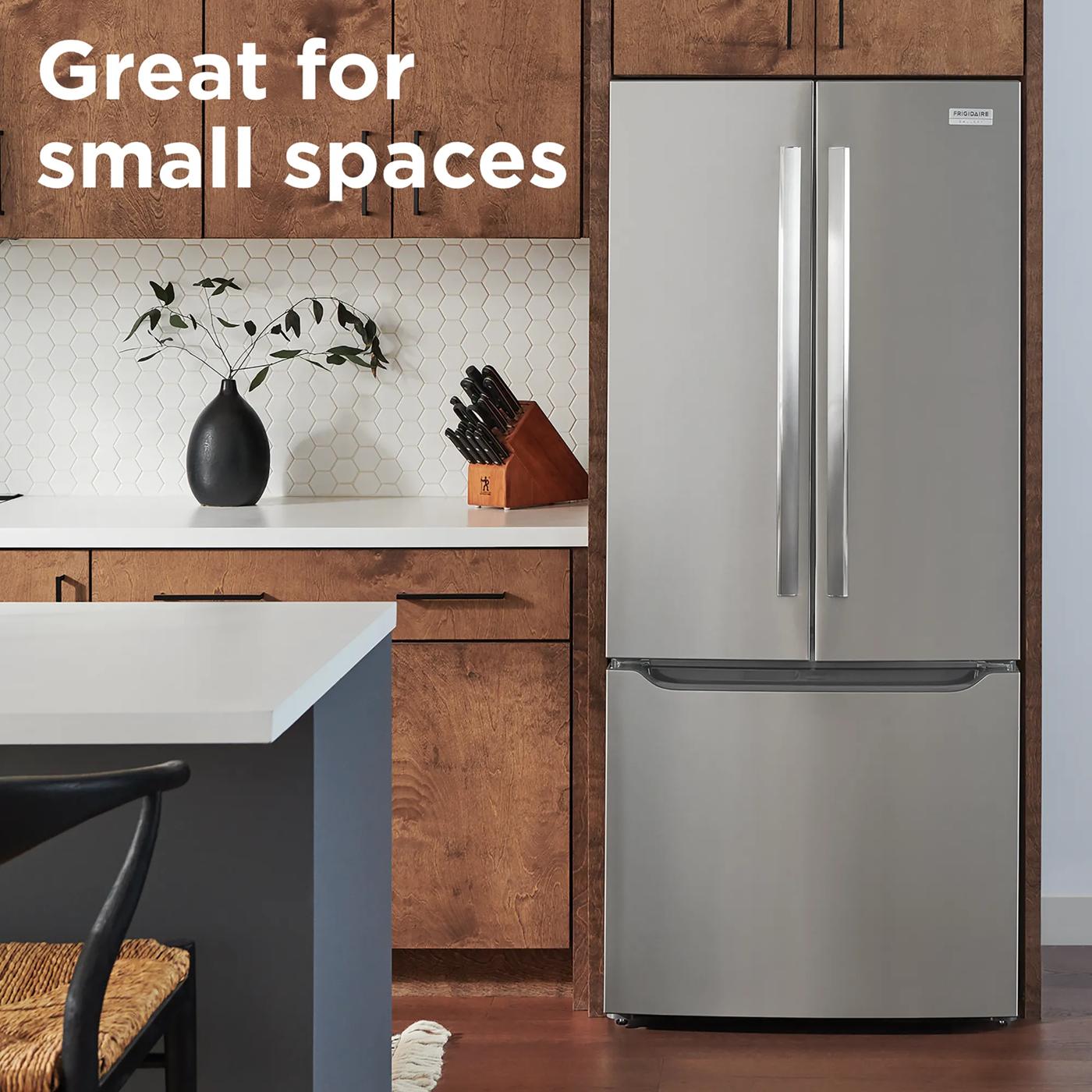 Stainless steel French door refrigerator with bottom freezer in modern kitchen featuring wood cabinets and white backsplash