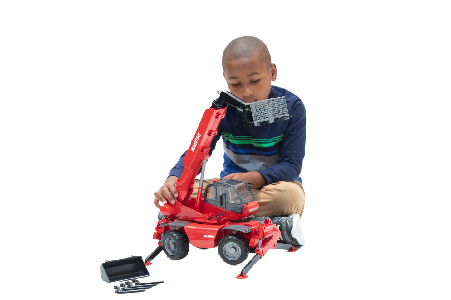 Boy playing with red Bruder Manitou telehandler toy featuring extendable arm and bucket attachment for construction play