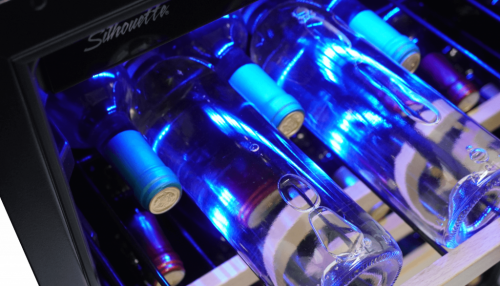 Close-up of blue LED-lit wine bottles resting on wooden shelves inside a single zone wine cellar in kitchen appliances collection