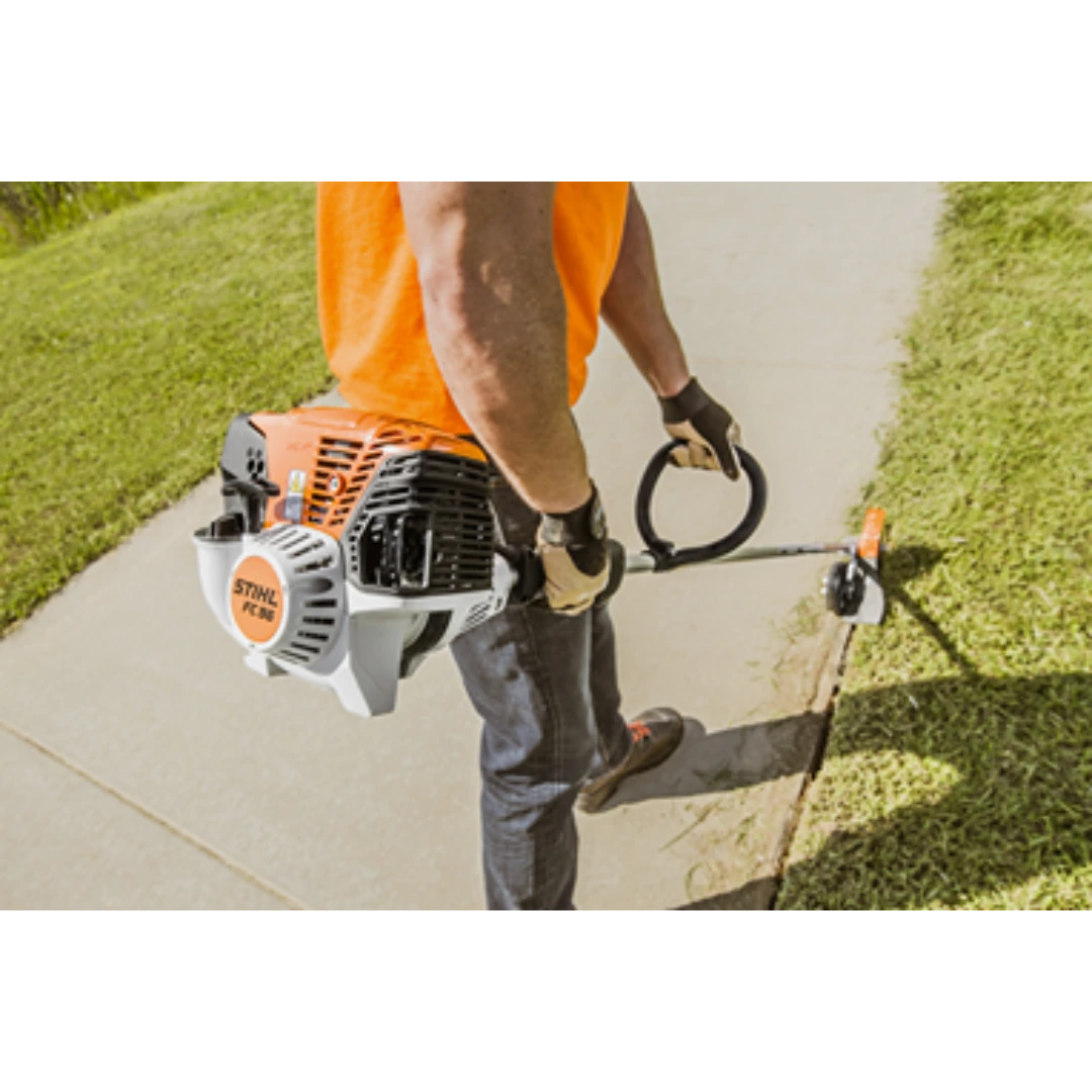 Person using STIHL straight shaft edger trimming grass along a concrete sidewalk for home improvement tasks