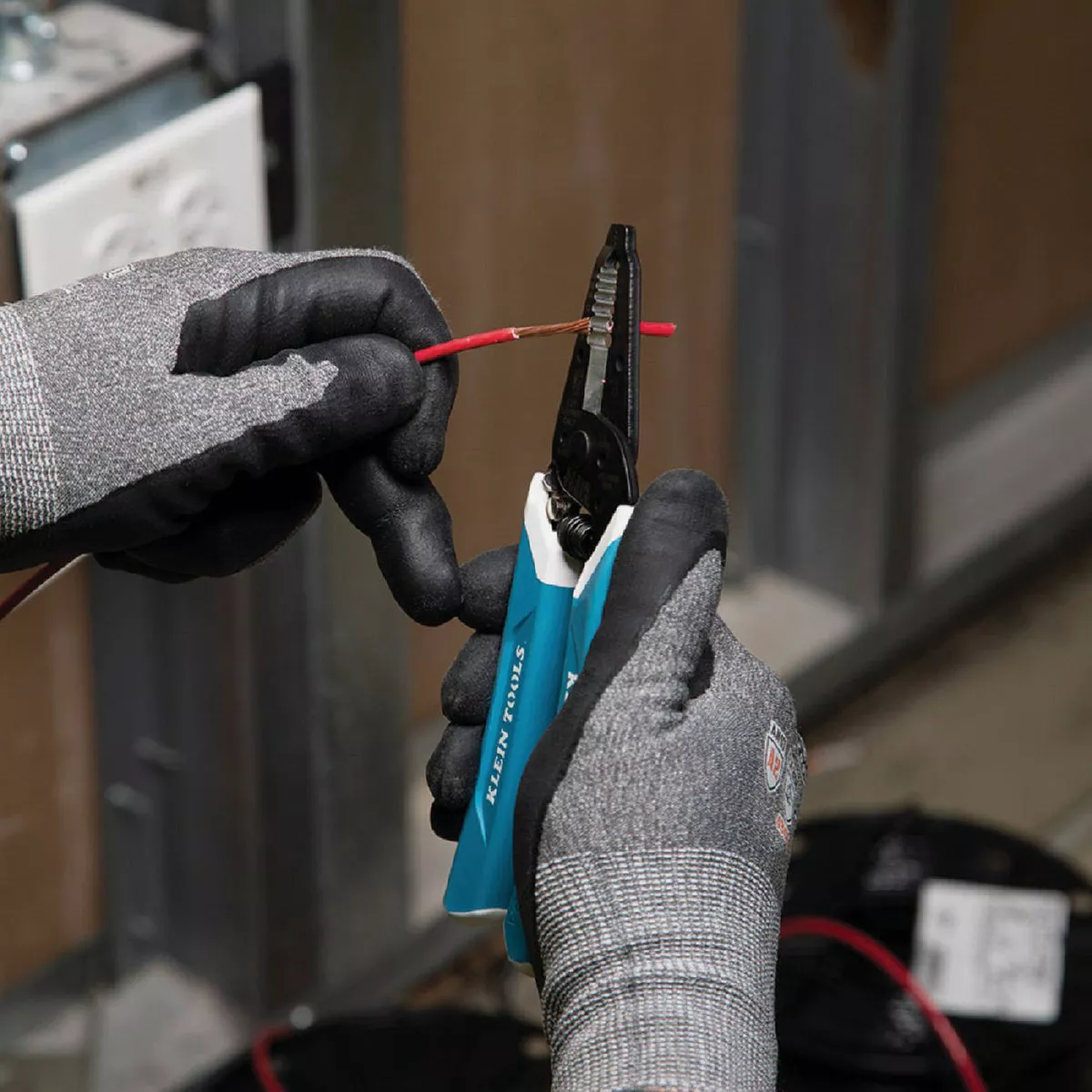 Wire stripper with blue handles cutting red insulated electrical wire for home improvement and tools use