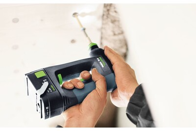 Hands operating a Festool cordless drill with ergonomic grip and green accents for home improvement tasks