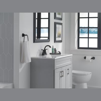 Matte black two-handle centerset bathroom faucet installed on a white vanity in a bright bathroom setting