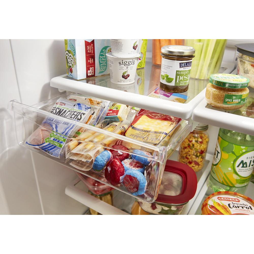 Clear deli drawer in refrigerator filled with assorted packaged cheeses, meats, and dairy products in kitchen appliance interior