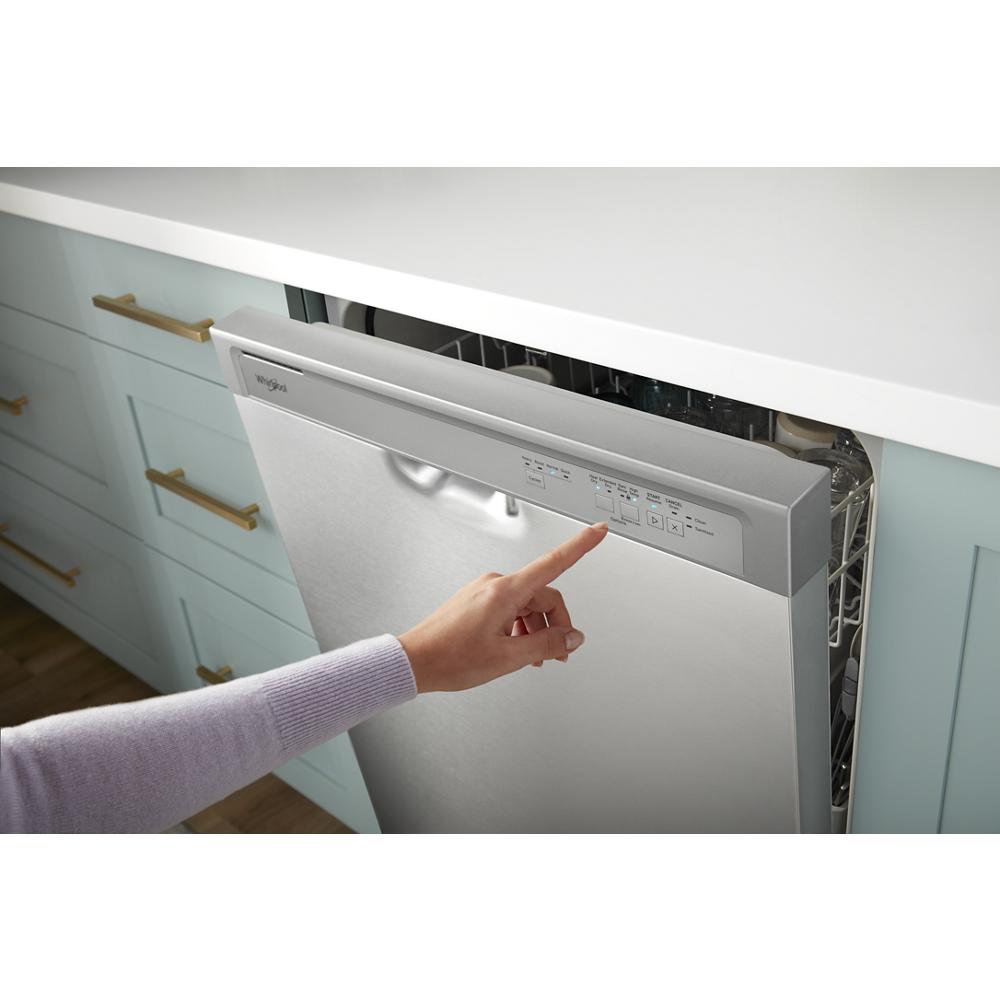 Person selecting settings on a stainless steel dishwasher integrated into light blue kitchen cabinetry with brass handles