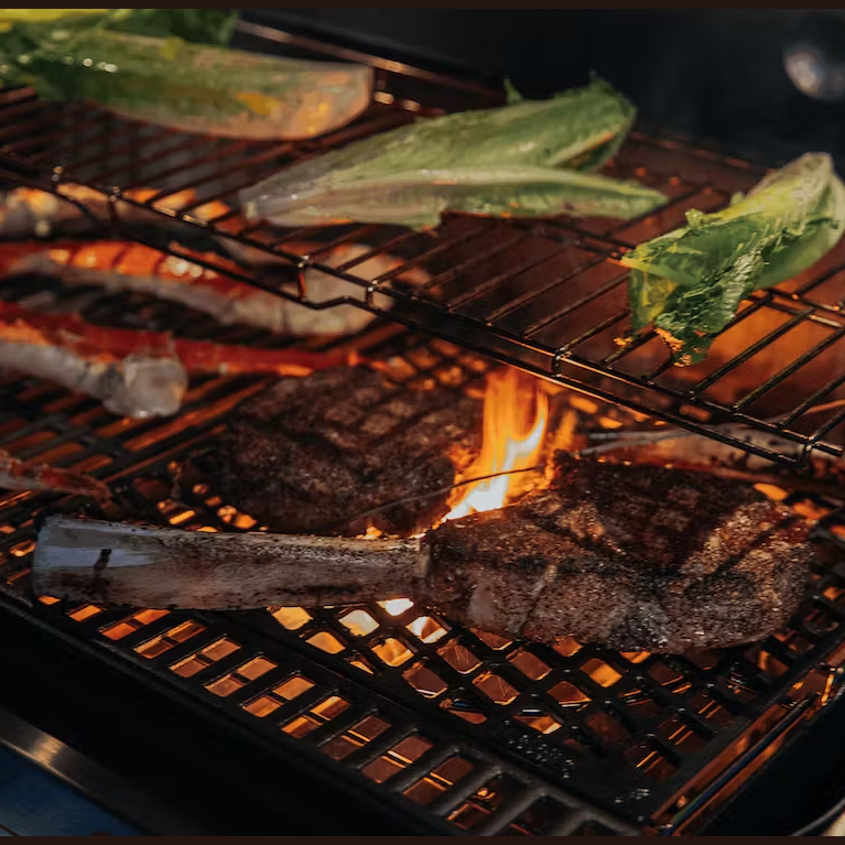 Cast iron dual-sided sear grate grilling steaks and vegetables with flame, ideal for outdoor cooking and grill accessories