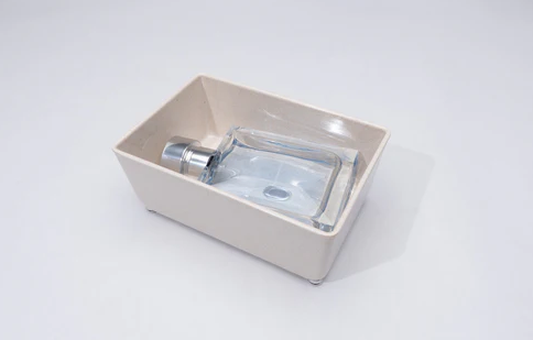 Natural bamboo melamine organizing tray holding rectangular glass bottle, ideal for kitchen or countertop storage