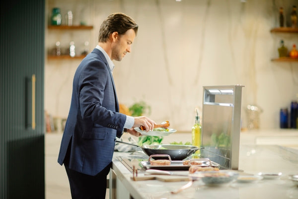 Man preparing food by stainless steel downdraft ventilation system in modern kitchen for home improvement use