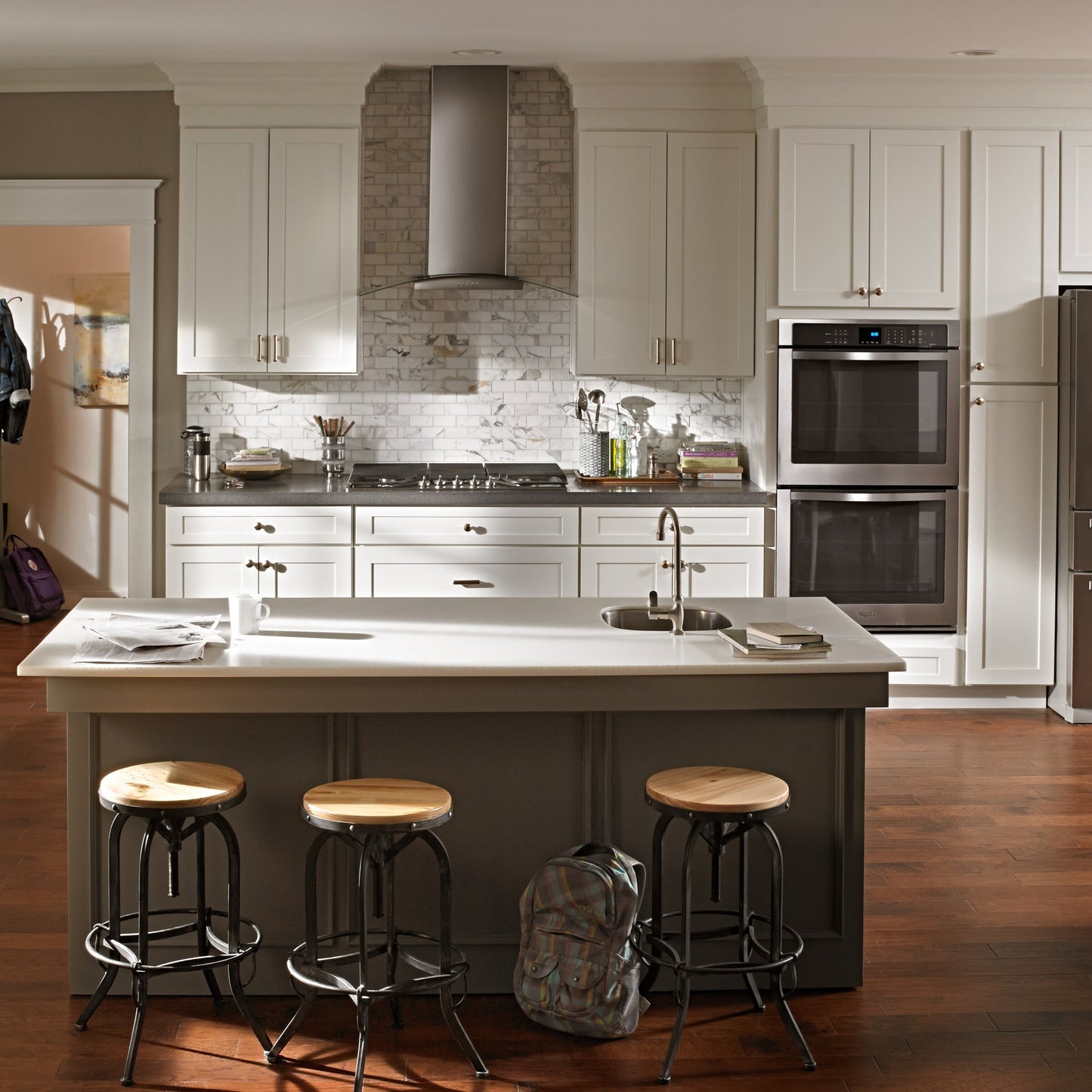 Sleek stainless steel 30" modern glass wall mount range hood above stove in bright kitchen with island seating and hardwood floors