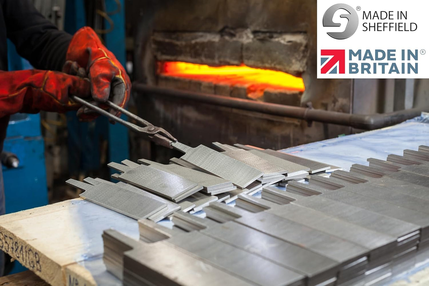 Gloved worker handling metal parts near forge in industrial workshop for woodworking tools manufacturing