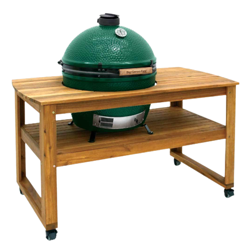 Green ceramic kamado grill nested in natural acacia wood table with lower shelf and caster wheels for outdoor grilling