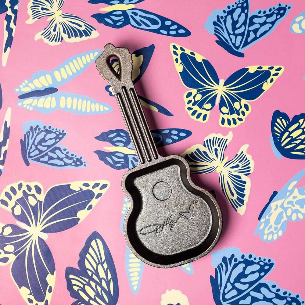 Small cast iron mini skillet shaped like a guitar with signature engraving on colorful butterfly background