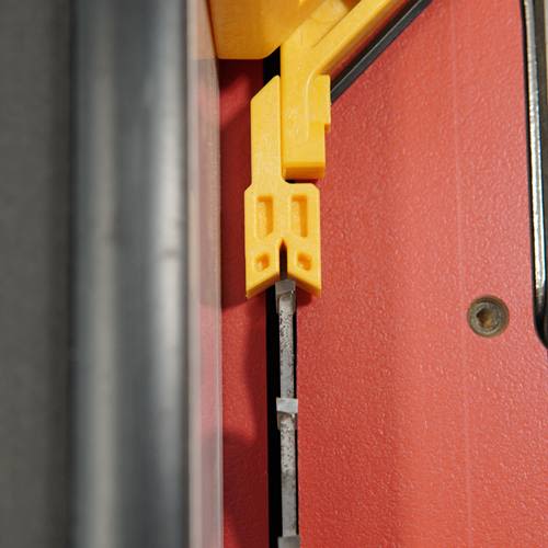 Close-up of yellow plastic woodworking gauge accessory attached to saw blade for precise tool alignment under $100