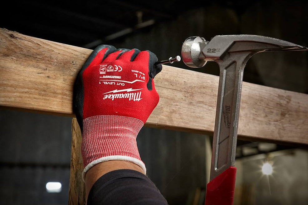 Worker wearing red and black nitrile coated gloves gripping hammer for home improvement and safety tasks