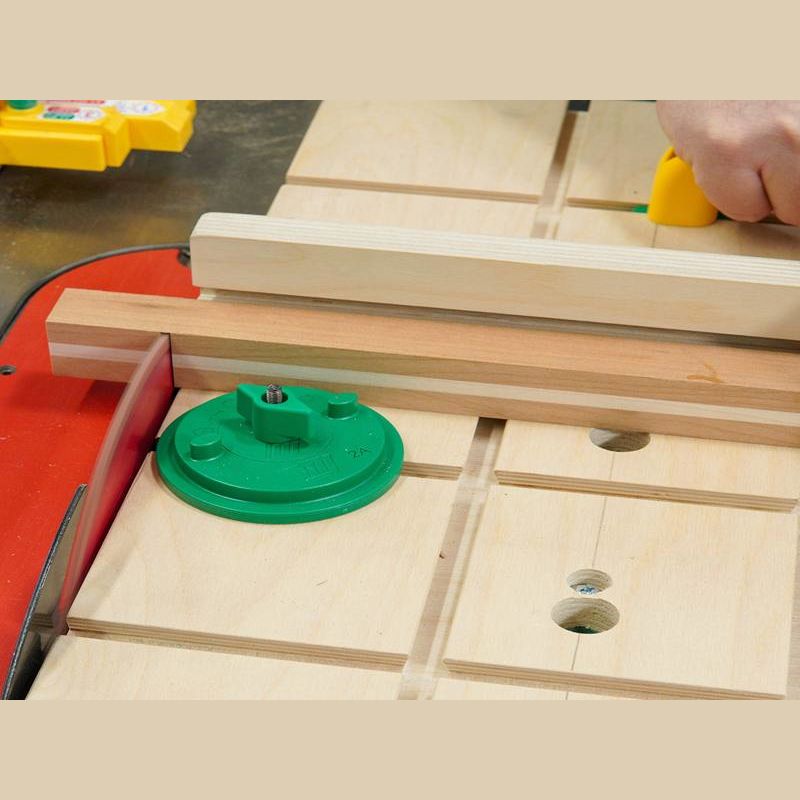 Wood pieces held by green circular clamp accessory on woodworking table saw for precise cutting tasks in home improvement