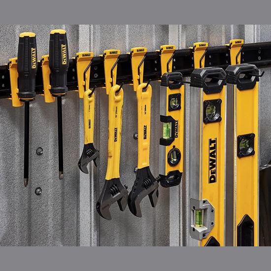 Yellow and black tool hooks holding screwdrivers, adjustable wrenches, and levels on metal rails for workshop organization.