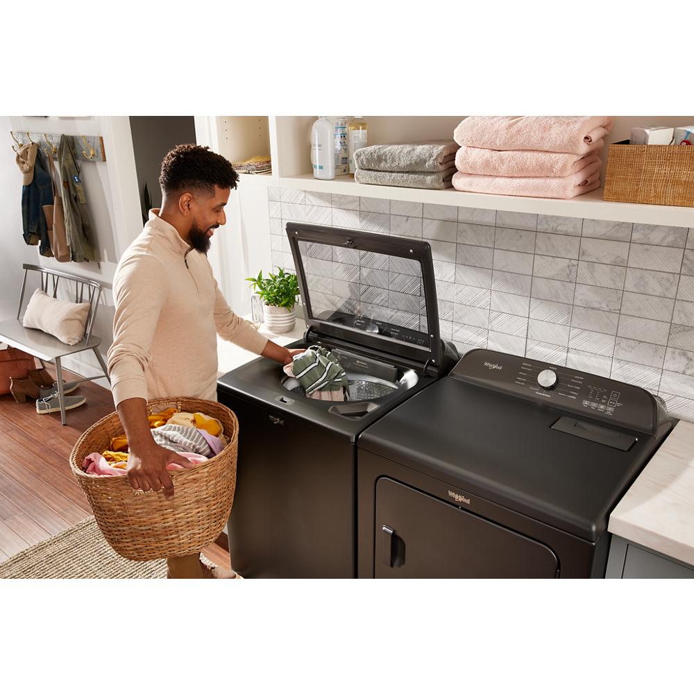 Matte black Whirlpool top load washer and matching dryer in a modern laundry room with white shelving and folded towels