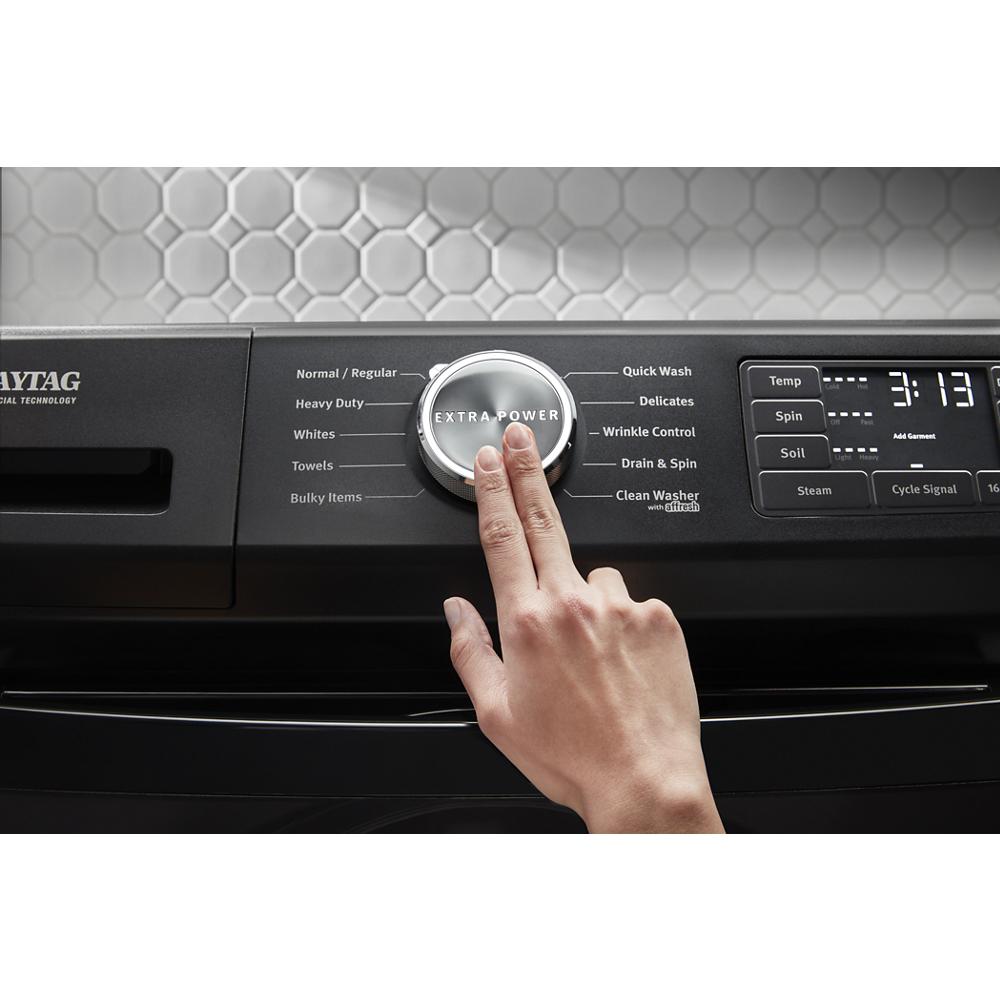 Hand adjusting the extra power cycle knob on a black front load electric dryer in a modern laundry setup